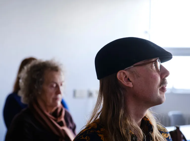 In front man with a black hat. In background two women.