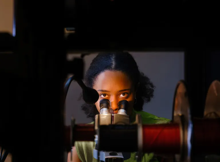 A student examines a sample under a microscope.