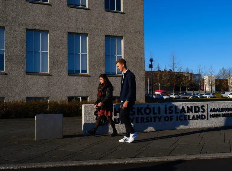 Two students walking in front of main building.