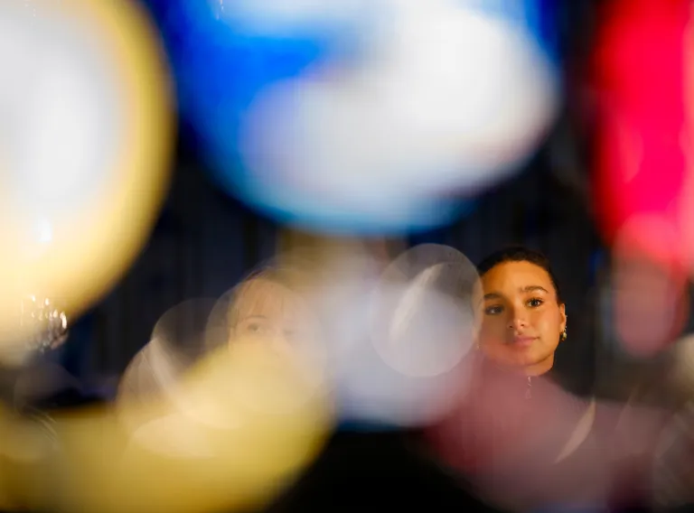 Blurred lights in front. Face of a woman in the back. 