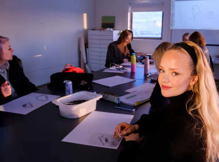 Woman drawing a bird in class with few other students