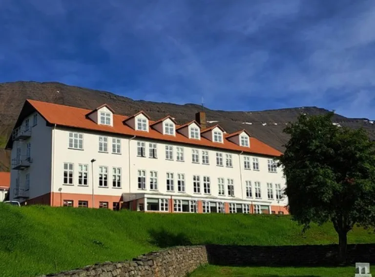 Aðalbygging Háskóla Íslands á Hólum Hjaltadal. Þriggja hæða hvítt hús með rauðu þaki og risgluggum.