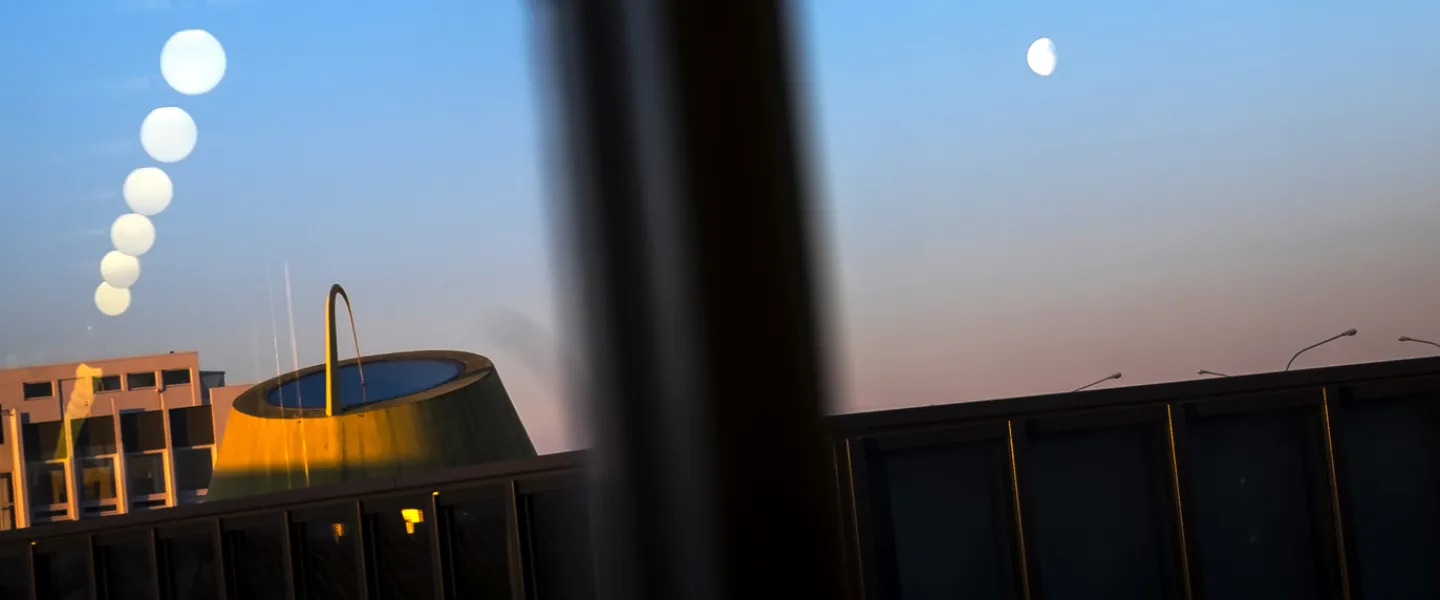 University centre, moon in the sky, lights reflecting from the window