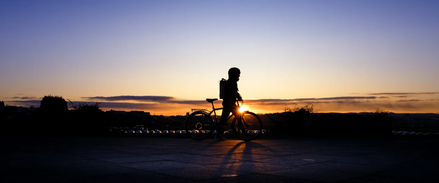 Silhouette of a person riding a bike outside University of Iceland Main building