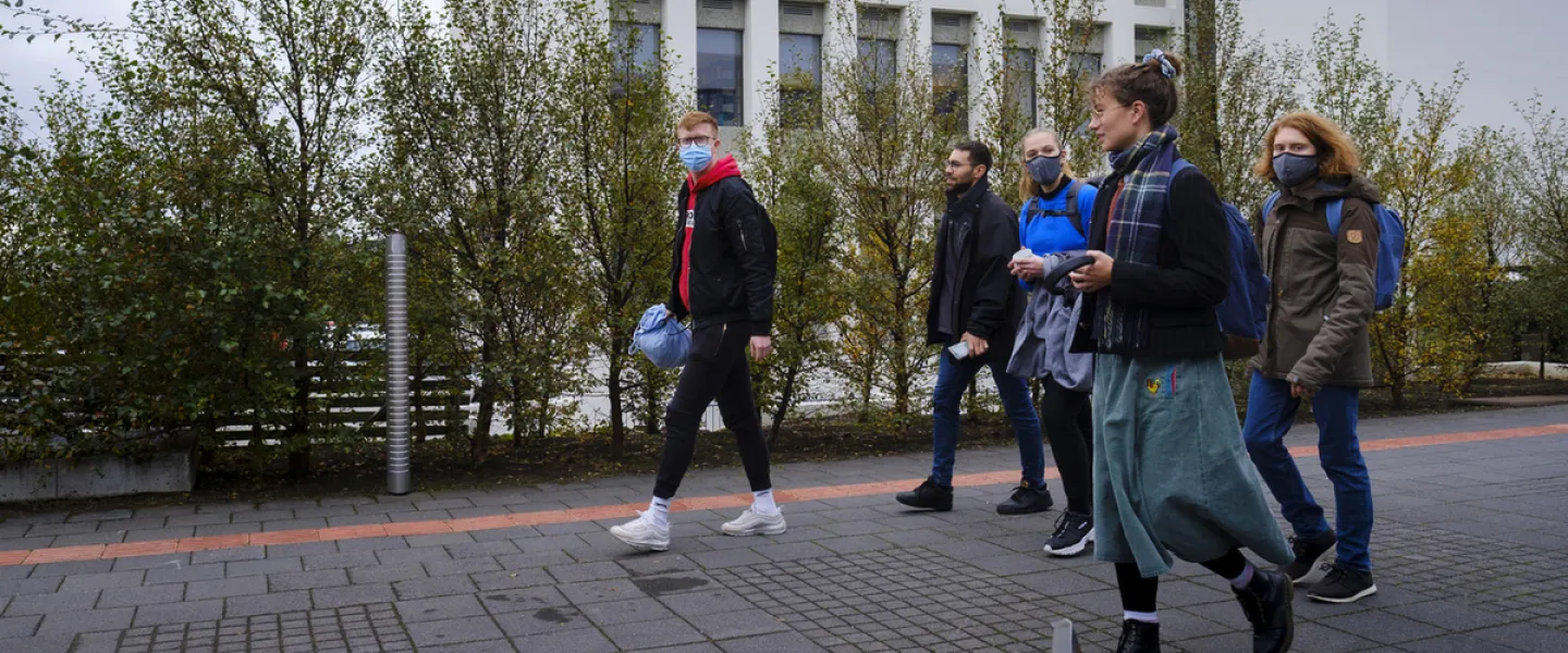 People with face masks walking outside of Lögberg