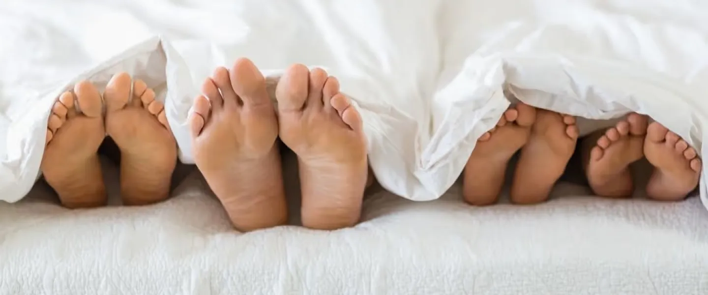 Bare feet of people lying in bed