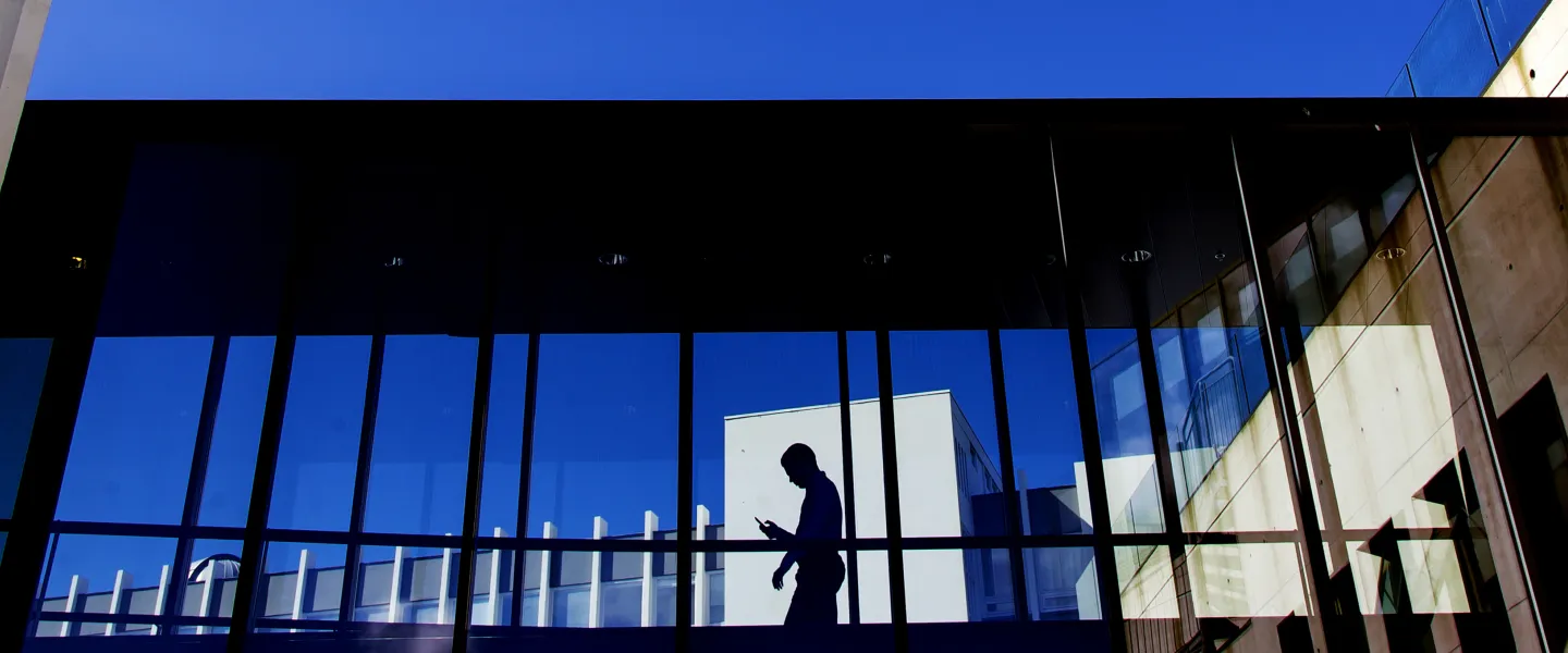 Person looking at their phone in the hallway between Gimli and Oddi