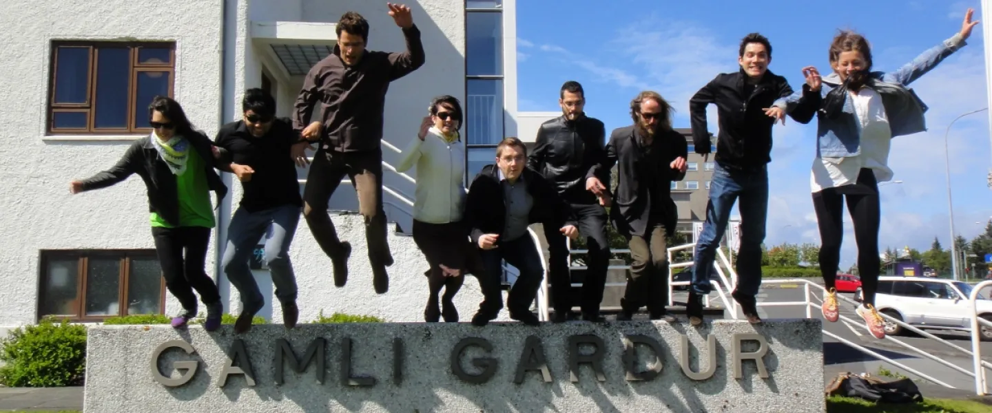 People jumping off the sign outside of Gamli Garður