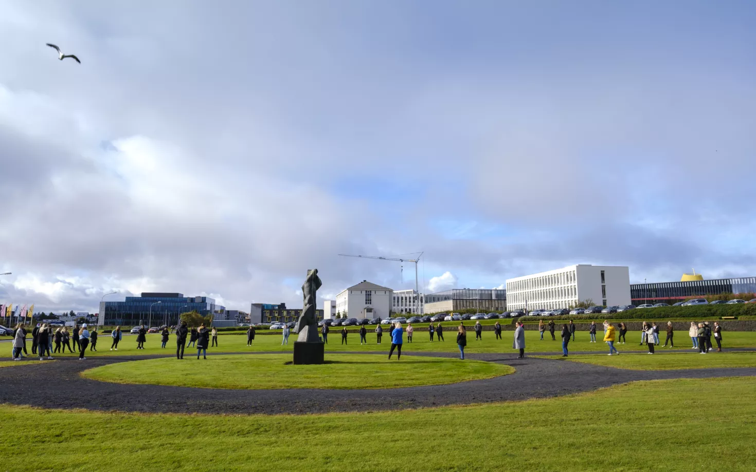 People standing on the grass in Skeifan outside of University of Iceland main Building