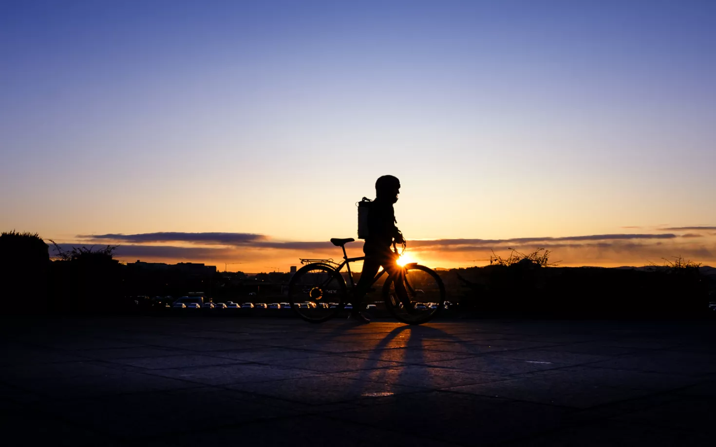 Silhouette of a person riding a bike outside University of Iceland Main building