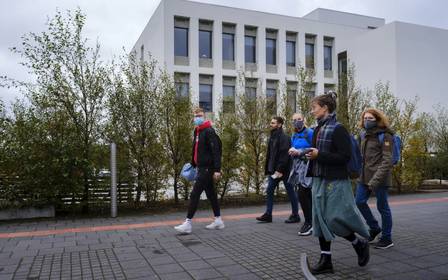 People with face masks walking outside of Lögberg