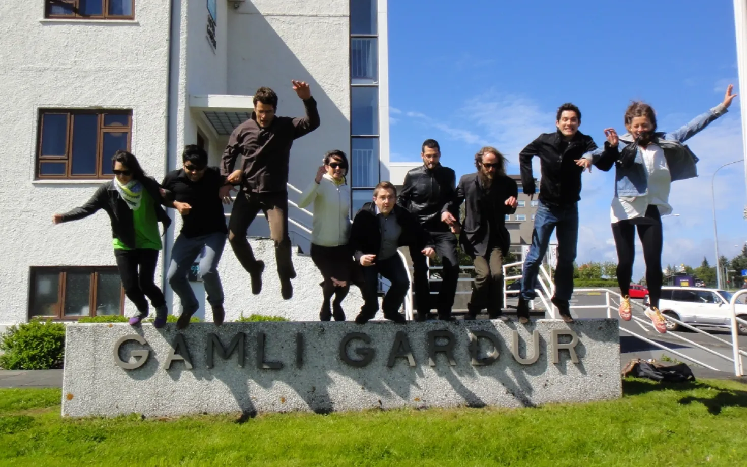 People jumping off the sign outside of Gamli Garður