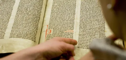 Finger pointing out word in old manuscript