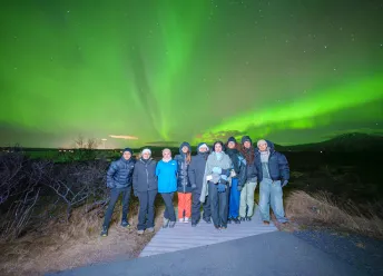 Aurora students standing outside under northern lights.