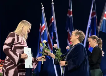 Silja Bára R. Ómarsdóttir, Rector of UI, handing a rose to a graduate at the graduation ceremony.