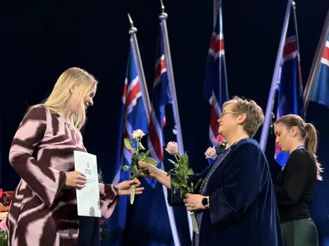Silja Bára R. Ómarsdóttir, Rector of UI, handing a rose to a graduate at the graduation ceremony.