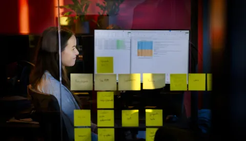 Woman sitting in front of acomputer, post-it-notes on a window