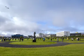 People standing on the grass in Skeifan outside of University of Iceland main Building