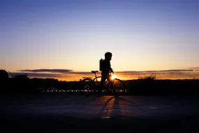 Silhouette of a person riding a bike outside University of Iceland Main building