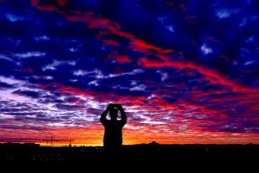 Silhouette of a man taking picture of the sunrise in Reykjavík. Perlan in the background