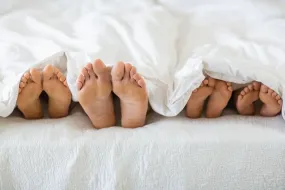 Bare feet of people lying in bed