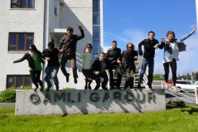 People jumping off the sign outside of Gamli Garður